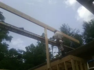 Carpenter setting a ridge beam over a new addition frame — Ice Dam Removal by Roofing Brothers in Murdock