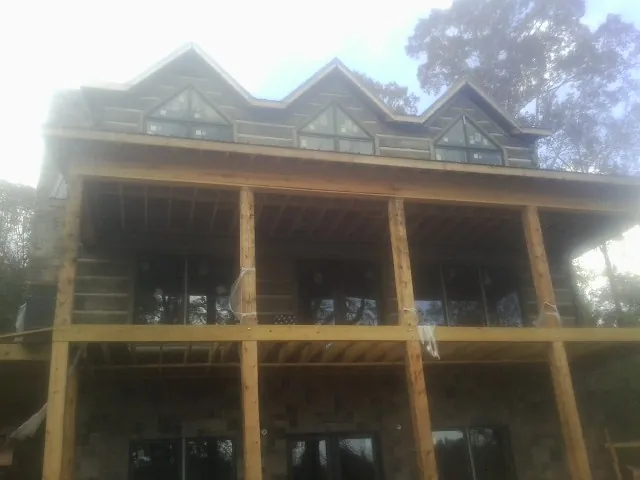 Dormers and porch framing on a large log home under construction — Roof Coating work by our crew in Murdock