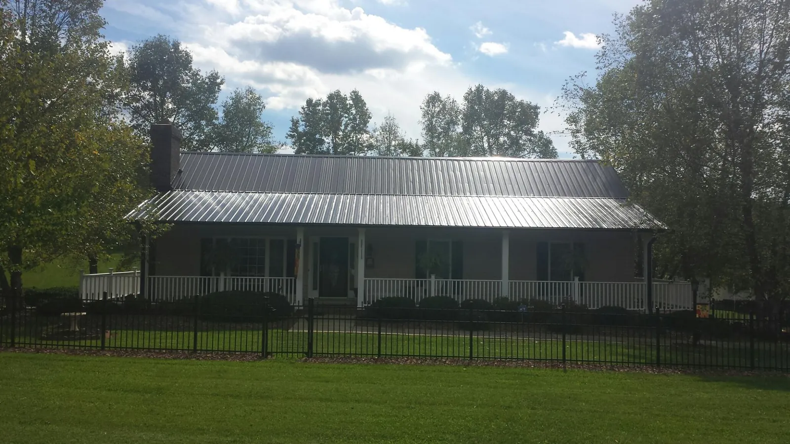 Gray metal roof on a brick ranch with a full width front porch — Gutter Guard Installation work by our crew in Murdock